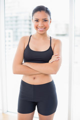 Smiling dark haired model in sportswear posing with crossed arms