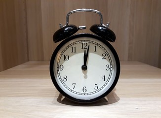 Black retro alarm clock on wooden cabinet