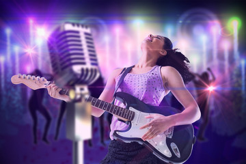 Obraz na płótnie Canvas Pretty girl playing guitar against digitally generated cool nightlife background