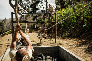 Young military soldiers practicing rope climbing during obstacle course