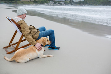 Man pampering dog while sitting on chair