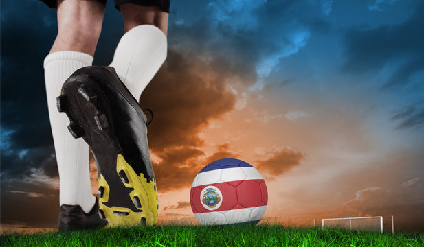 Composite image of football boot kicking costa rica ball against green grass under blue and orange sky