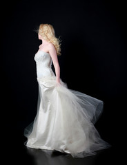 Fototapeta na wymiar full length portrait of woman wearing white bridal gown. standing poison black studio background.