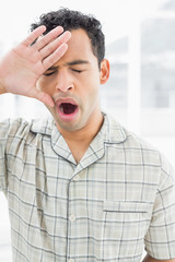 Closeup of a young man yawning in bed