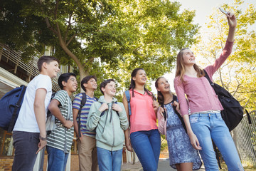 Fototapeta premium Happy students taking selfie on mobile phone in campus