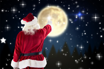 Santa Claus points at something against twinkling stars