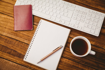 Pen on notepad next to cup of coffee passport and keyboard