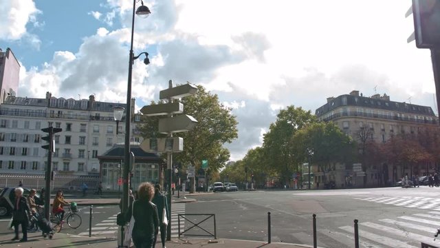 PARIS, FRANCE - SEPTEMBER 29, 2017: Timelapse shot of walking along roadside sidewalk lined with trees. Passing by stores and cafes, view on sunny day