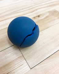 Broken blue racquetball on court floor