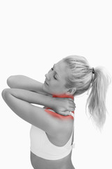 Side view of sporty young woman massaging neck over white background