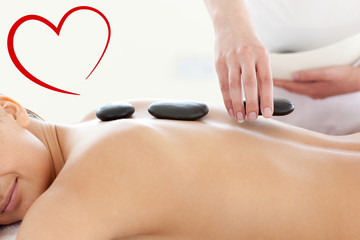 Portrait of a beautiful woman having a massage with stones  against heart