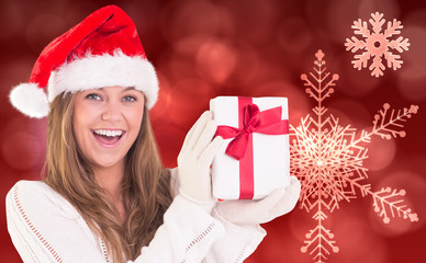 Festive blonde holding a gift against red snow flake pattern design