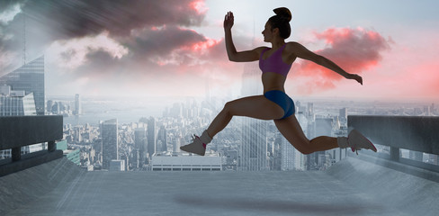 Fototapeta na wymiar Fit brunette running and jumping against sun shining over road and city