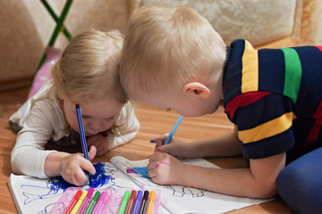Little children draw in the album with pencils