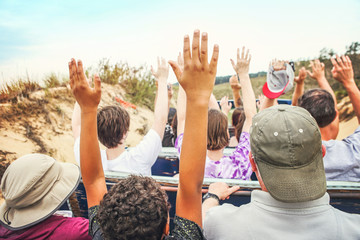 People with hands raised on a sand dune tour ride
