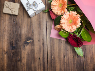 Bouquet of flowers on old wooden background with gift boxes, top view. Decoration from flowers of chrysanthemums, daisies decorative plants for birthday card. Selective soft focus, blurred backdrop