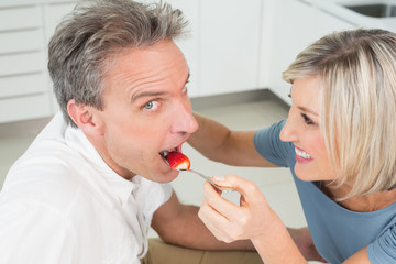 Loving woman feeding man in kitchen