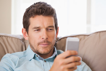 Young man text messaging in living room