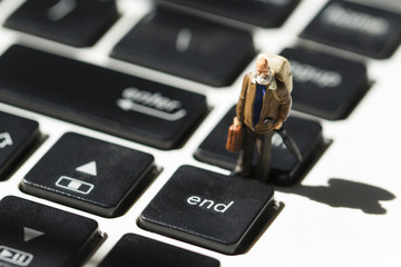 Old man on white notebook keyboard. Computer keyboard closeup with focus on End button.