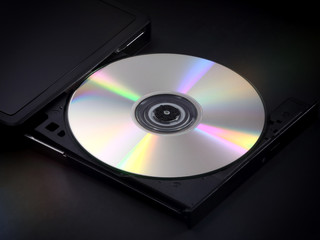 A silver, shiny CD is shown ejected in the tray of a portable multimedia disc player.