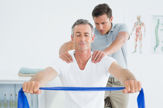 Therapist massaging mans shoulder in hospital