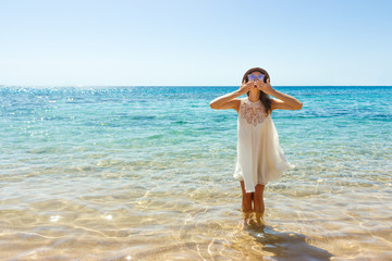 Fototapeta na wymiar girl sends an air kiss to the camera. a beautiful carefree Woman relaxing at the beach enjoying her sun white dress