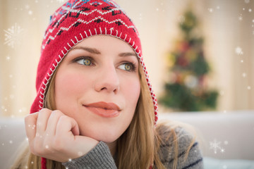 Woman in winter hat thinking with head on hand against snow falling