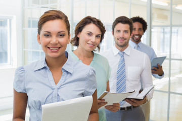 Business colleagues holding notepads in row at office