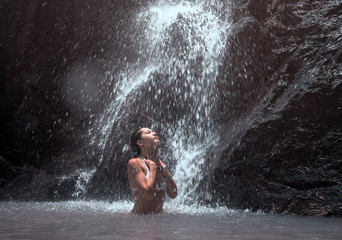 Beautiful young woman enjoy a waterfall.