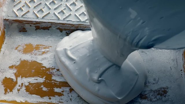 overthrow white color paint in to yellow tray for painting work and design