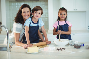 Mother and kids preparing cookies in kitchen