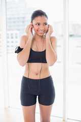 Joyful dark haired model in sportswear listening to music