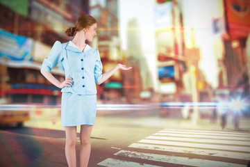 Pretty air hostess presenting with hand against blurred new york street
