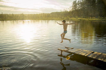 Fototapeta na wymiar A young man jumps into the lake.