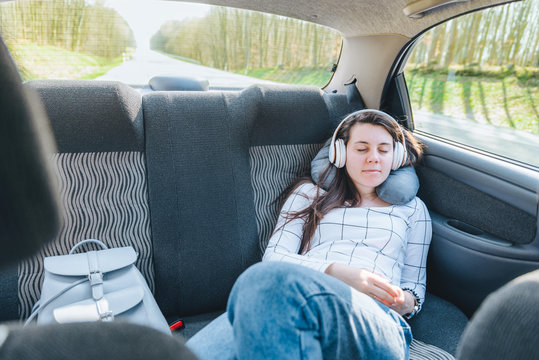 woman sleeping in car at backseat and listening music in headset. travel concept