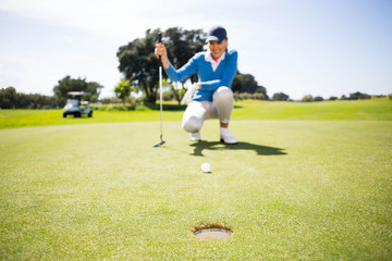 Obraz premium Female golfer putting her ball 