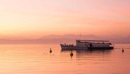 Beautiful sunset over Garda lake with ship swimming, Sirmione.