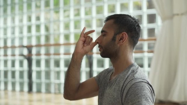 Man practicing pranayama in sunny yoga studio at sunrise rapid slow motion