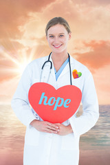 The word hope and doctor holding red heart card  against sunrise over magical sea