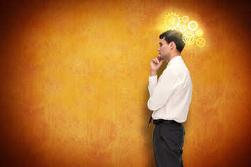 Thoughtful young businessman looking away against orange background 