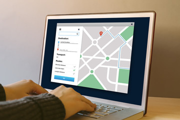 GPS map navigation app on laptop computer screen on wooden table. Hands typing on a keyboard....