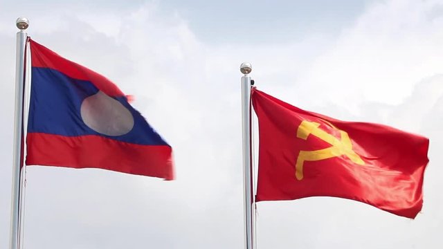Lao National Flag with red flag with communist symbols of a sickle with a hammer flying in a sky, Laos