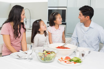 Smiling family of four sitting at dining table in kitchen