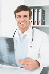Smiling doctor with xray picture of spine in the medical office
