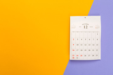 Calendar page on bright bicolor background, top view