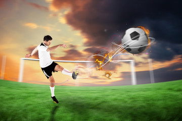 Obraz na płótnie Canvas Football player in white kicking against football pitch under cloudy orange sky