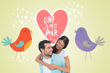 Happy casual man giving pretty girlfriend piggy back against love birds with heart and dandelions