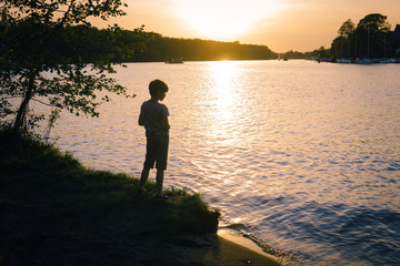 Boy standing on river at sunet