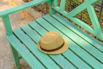 Brown hat on green wooden bench in the park