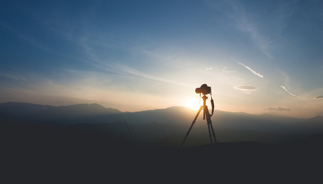 Silhouette of a camera on a tripod. Shooting sunset in the mountains